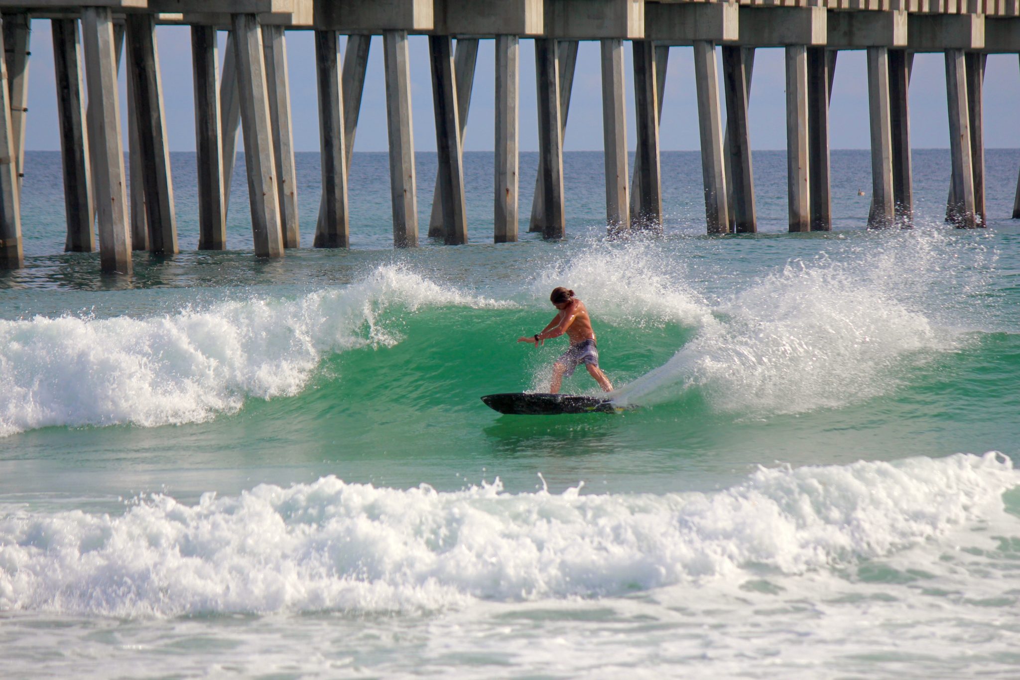 This weekend, Hurricane Harvey joined past mega-storms like Katrina and Sandy in the annals of American history: a devastating storm that claims lives, destroys homes, wreaks havoc on major metropolitan areas, and stretches infrastructure and emergency services to their breaking point while also delivering excellent surf to certain corners of the East Coast. Austin Magee enjoys the Florida Panhandle flipside of Harvey’s hell in Houston for our August 27, 2017 Photo of the Day taken by Henry Connart. Keep the thoughts and prayers flowing toward Southeast Texas and do what you can to contribute to the ongoing relief effort